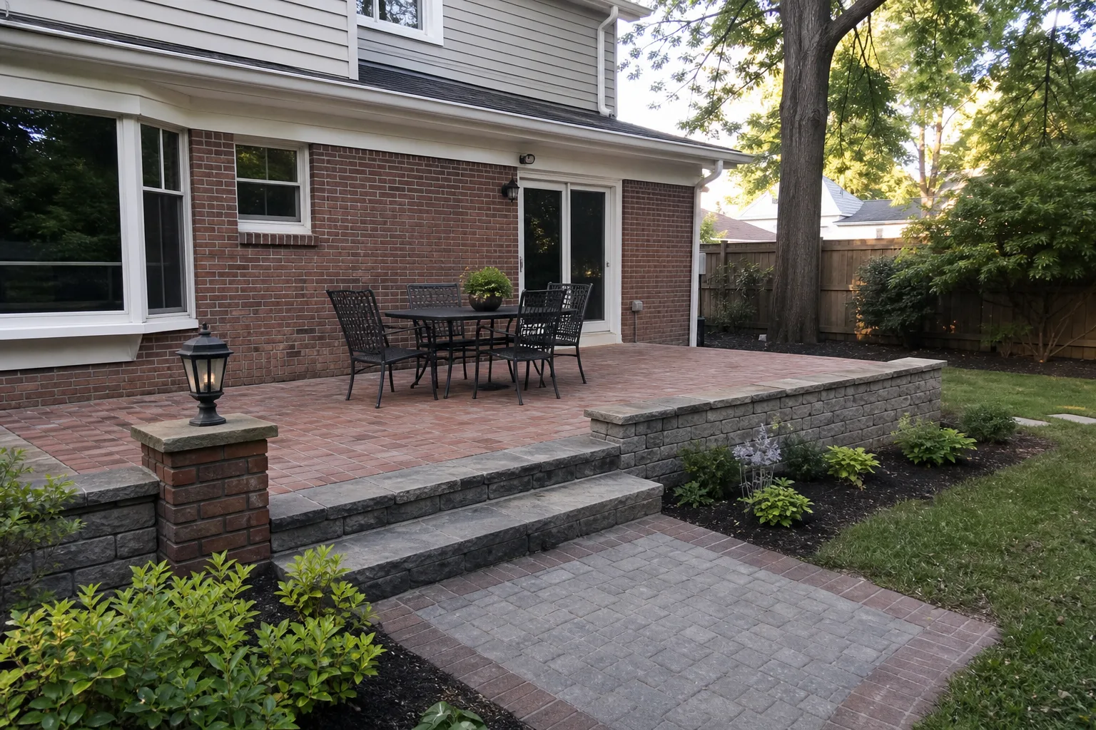 Brick patio, stone steps, low retaining wall, and planting beside a family home